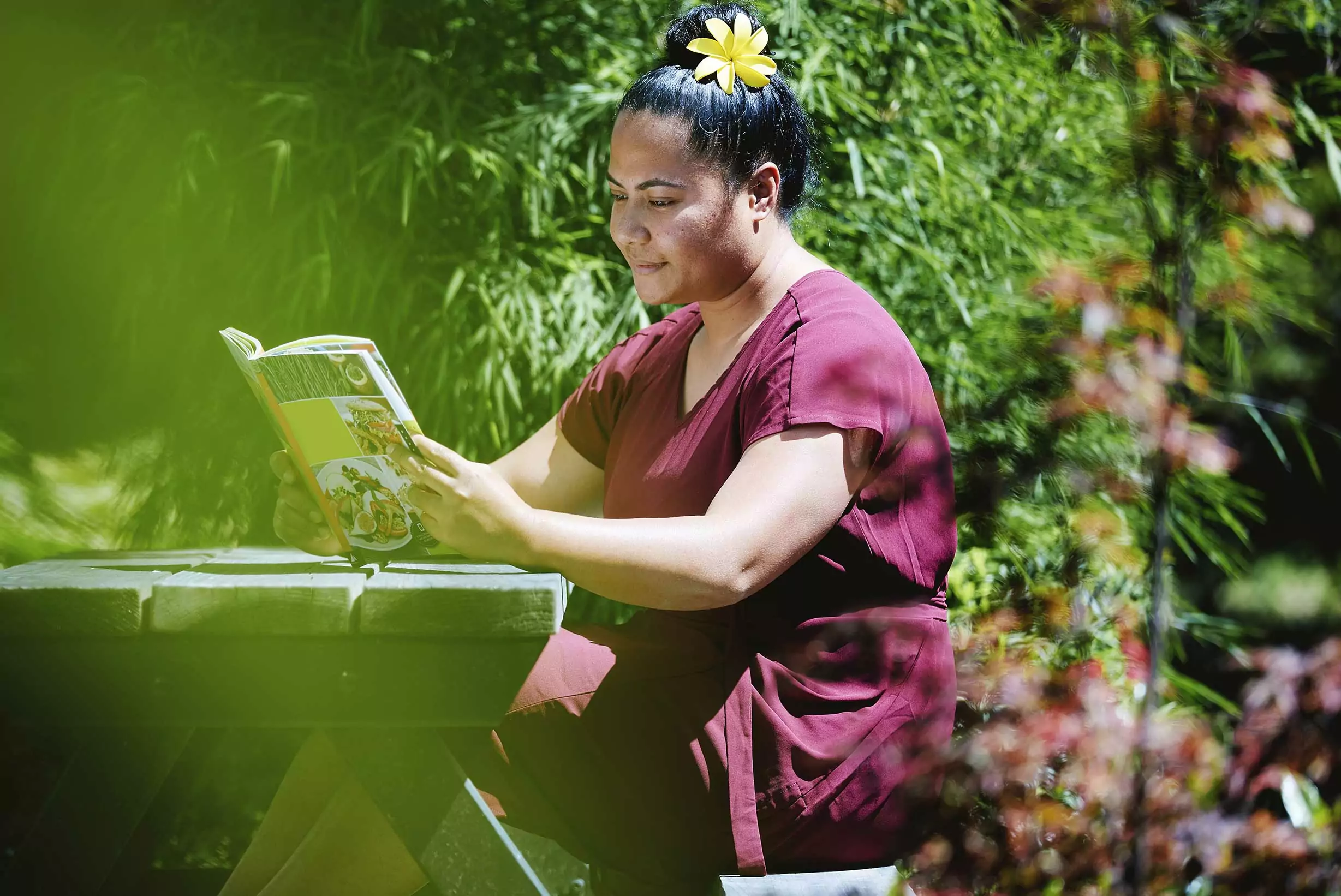 Pacifika woman sitting in a beautiful garden reading a book
